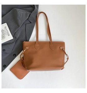 Brown leather tote bag and zipper pouch set displayed with professional attire accessories