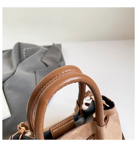 Détail des poignées en similicuir et texture daim d'un sac seau bicolore marron