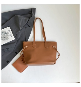 Detailed view of brown leather tote bag with matching inner pouch and gold hardware