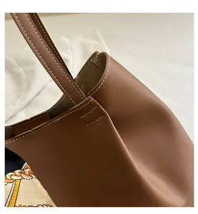 Gros plan du sac fourre-tout en cuir marron mat avec des coutures contrastées blanches