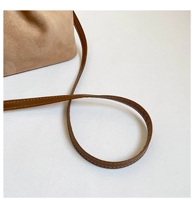 Gros plan d'un sac à bandoulière en daim marron avec coutures fines sur la sangle