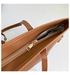 Macro detail of brown tote bag showing golden zipper and herringbone fabric lining