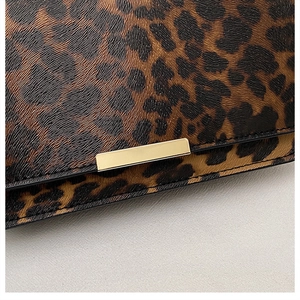 Close-up of leopard print handbag featuring high-quality leather texture and gold metal buckle