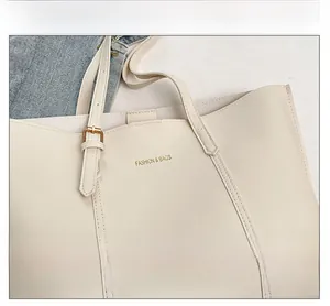 Detail of off-white leather tote bag featuring gold FASHION & BAGS lettering and metal buckle