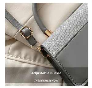 Detail of adjustable metal buckle and textured woven fabric on gray shoulder bag