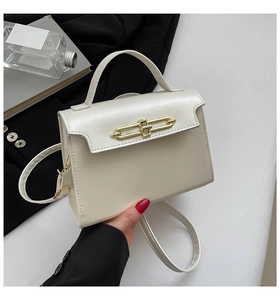 Detailed shot of cream white leather bag featuring a polished gold oval twist lock