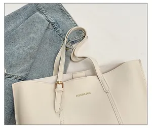 Detail of cream tote bag featuring adjustable thin strap with gold metal buckle