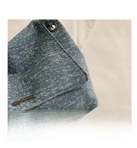 Détail du sac cabas en jean avec ornements en métal noir et texture de tissu robuste