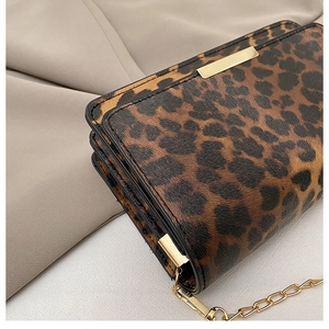 Detail of leopard print crossbody bag showing gold metal hardware and side accordion pleats