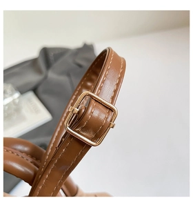 Gros plan sur la bandoulière en cuir marron avec boucle réglable en métal doré brillant