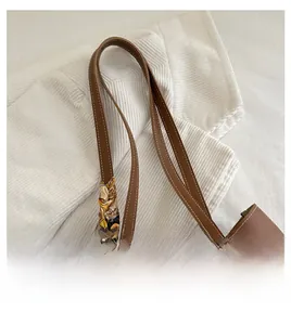 Détail du sac cabas en cuir marron avec surpiqûres blanches et accessoire de foulard en soie