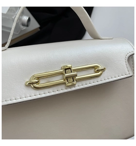 Detail of elegant beige tote bag featuring a golden chain-link twist lock and fine stitching