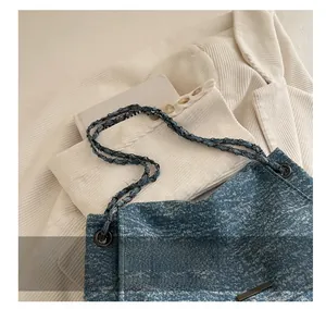Détail de la texture denim et bandoulière en chaîne du grand sac fourre-tout