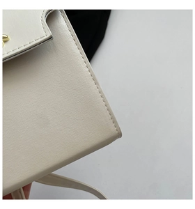 Close-up of precise stitching and lychee grain leather texture on a beige tote bag
