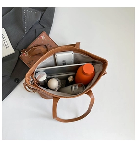 Internal view of a large brown tote bag showing storage for laptop and daily essentials