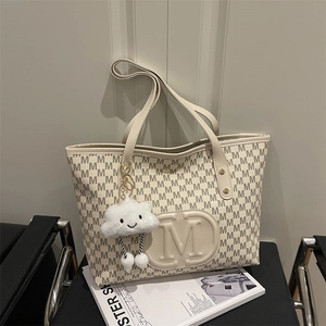 Detail of monogram tote bag with M logo, cloud charm, and versatile shoulder straps