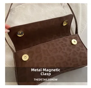 Detailed view of dual magnetic golden snaps on brown leopard print suede bag
