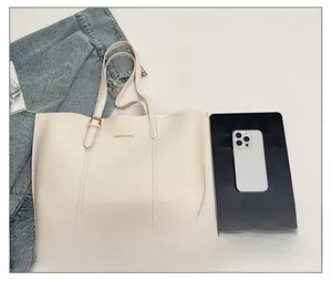 Detailed view of cream tote bag capacity showing it holds a tablet and smartphone
