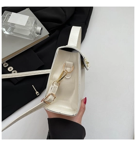 Detail of white glossy leather bag showing gold D-ring hardware and adjustable shoulder strap