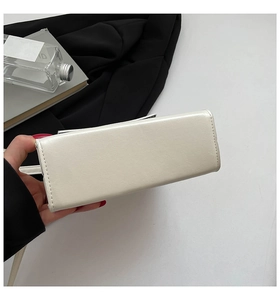 Detailed close-up of precise stitching on the bottom of this beige leather square bag