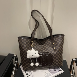Detail of dark brown tote bag with M monogram print and white cloud charm accessory