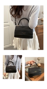 Detail of black square handbag showing glitter top, matte finish, and gold hardware