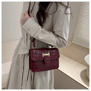 Detail view of burgundy stone pattern shoulder bag with a gold metal H-shaped buckle