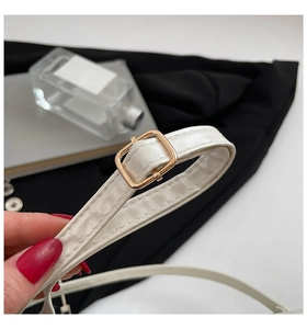 Detail of white leather shoulder strap with gold adjustable buckle and precise stitching