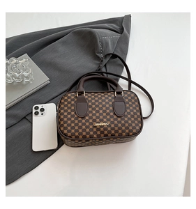 Detail of vintage brown square handbag with monogram pattern and golden hardware