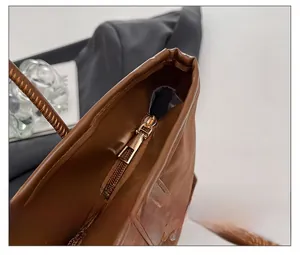 Detailed macro shot of the smooth gold metal zipper and brown leather grain on tote bag