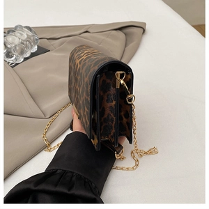 Detail view of leopard print crossbody bag with gold chain strap and layered structure