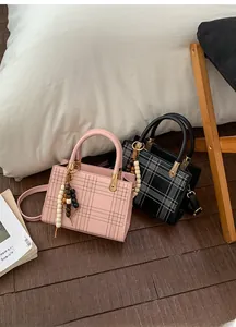 Dettaglio delle borse tote a quadri rosa e nere con nappe decorative in perline di legno