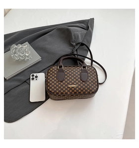 Flat lay of a brown monogram Boston bag with gold logo and long shoulder strap