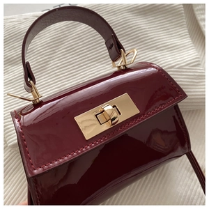Detailaufnahme der glänzenden bordeauxroten Lackleder-Mini-Tasche mit goldenem Verschluss