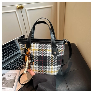 Vue détaillée du sac à main en laine à carreaux avec poignées en cuir et pompon en perles