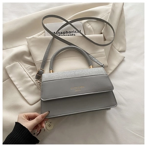 Detailed top view of a grey fashion handbag with silver sequins on beige blazer
