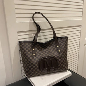 Detail of dark brown tote bag showing repetitive M letter print and embossed logo