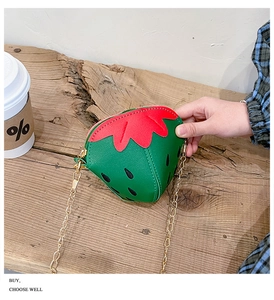 Dettaglio della mini borsa a tracolla a fragola con catena dorata e zip di chiusura