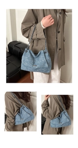 Détail du sac cabas en tweed bleu avec plaque logo métal et bandoulière chaîne