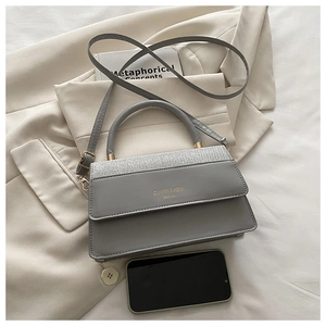 Detail of grey square crossbody bag with silver sequins and metallic logo on blazer