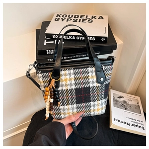 Détail d'un sac cabas à carreaux avec pompon perlé sur des livres vintage