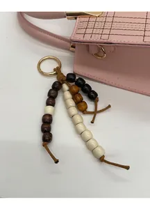 Dettaglio di ciondolo in perle colorate con chiusura in metallo dorato su borsa a mano