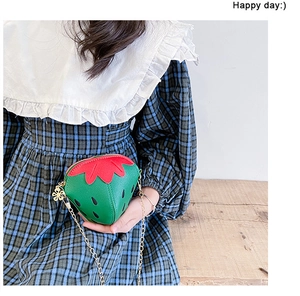 Dettaglio delle foglie di fragola rosse e catena dorata sulla borsa verde bimba
