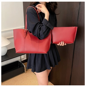 Detail of red large tote bag and matching clutch set with lychee grain texture finish