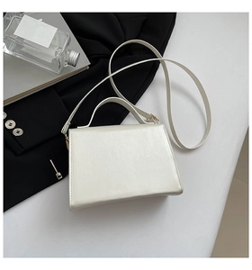 Close-up of white structured tote bag with gold hardware and smooth pearlescent finish