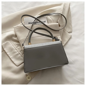 Macro shot of grey leather crossbody bag showing silver glitter flap and gold hardware