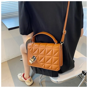 Détail d'un sac bandoulière matelassé marron avec surpiqûres en losange et boucle dorée