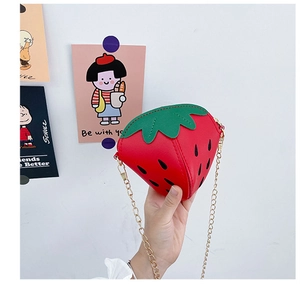Dettaglio di una borsa a tracolla a fragola con catena in metallo dorato per bimbi