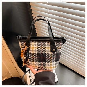 Détail du sac cabas en tweed à carreaux avec poignée en cuir et pompon en perles colorées