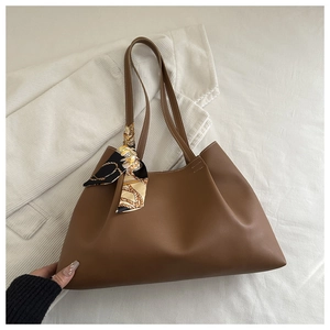 Détail d'un sac cabas marron caramel avec un foulard décoratif en soie sur la poignée